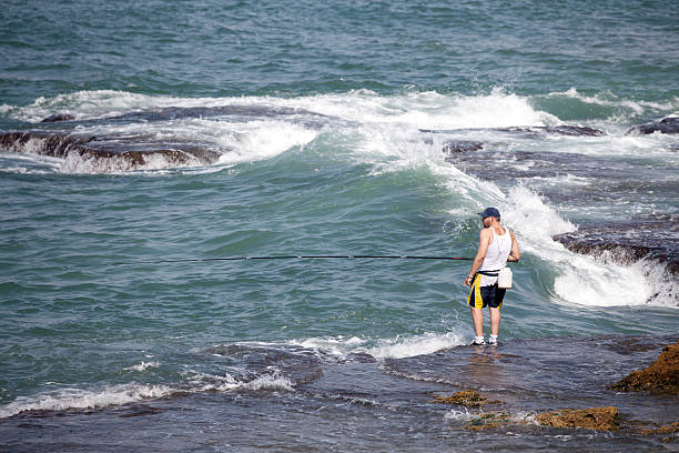 Beirut, Lebanon - October 1, 2011: A young man fishing in a stormy sea.
