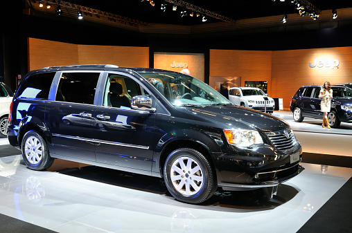 Amsterdam, The Netherlands - April 12, 2011: Black Lancia Grand Voyager Multi Purpose Vehicle on display at the 2011 Amsterdam Motor Show. Models are standing next to the cars in the background. The 2011 Amsterdam motor show was running from April 12 until April 23, in the RAI event center in Amsterdam, The Netherlands.