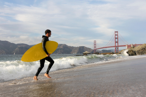 San Francisco, United States - October 3, 2011: A surfer walks out the water at Baker Beach, in front of the Golden Gate Bridge, in California. The beach saw San Francisco\'s only recorded shark attack when 18-year-old Albert Kogler Jr was killed by a great white on May 7, 1959.