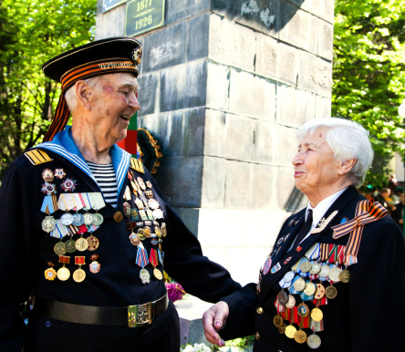 Portrait of a patriotic senior Scottish man wearing traditional kilt outdoors holding a Scottish flag