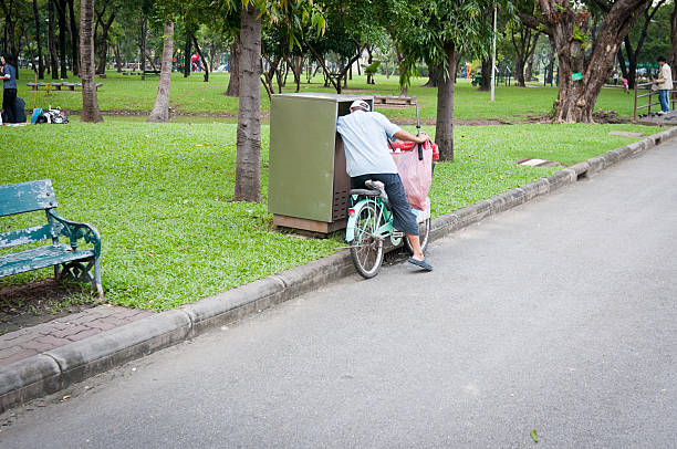 Bangkok, Thailand - October 21, 2010: A man collecting plastic from a bin in Lumphini Park in Bangkok, Thailand. Some people in Thailand make small amounts of money by collecting rubbish which can be recycled.