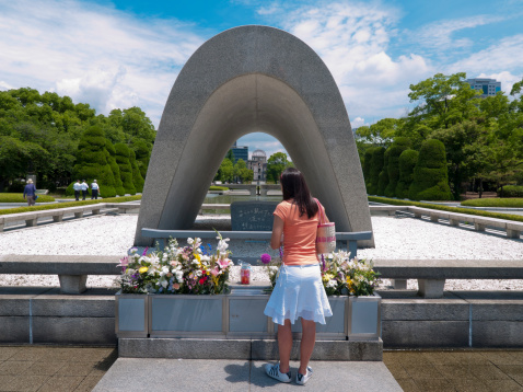 Hiroshima, Japan - June 23, 2007: Japanese girl stands in front of flowers at the Peace Park memorial, Hiroshima. The structure known as the \