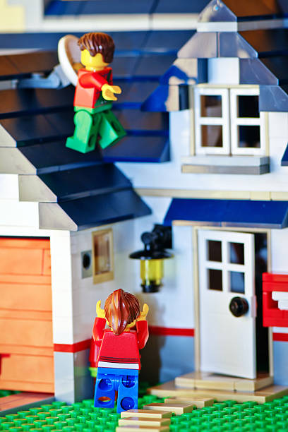 Borgosesia, Italy - October 10, 2011: Lego couple outside their new house built with the famous Lego construction block toys. The man is trying to fix the antenna but something went wrong and he is in danger of falling down. The woman is watching worried.