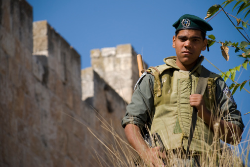 Jerusalem, Israel/Palestine - November 10, 2006: An Israeli border policeman stands outside the Old City walls of Jerusalem, watching people approaching an entrance. Border policemen often stand at the entrances to the Old City, doing random checks of Palestinian IDs.