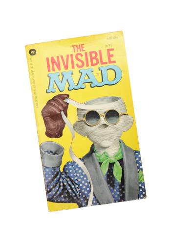 West Palm Beach, USA - July 9, 2011: This image shows a vintage paperback book titled The Invisible Mad, published by Warner Books in 1974. The Mad magazines and comic books were famous for their satire, parody, and lampooning of pop culture and the current politics, celebrities, and media. The cover features an invisible Alfred E Neuman, Mad's perennial mascot.
