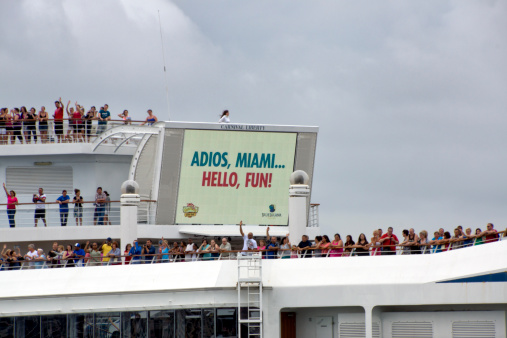 Miami, USA - April 28, 2012: A Carnival Cruise ship departs from the Port of Miami to join the Bahamas. The passengers say goodbye waving their hands from the upper decks.