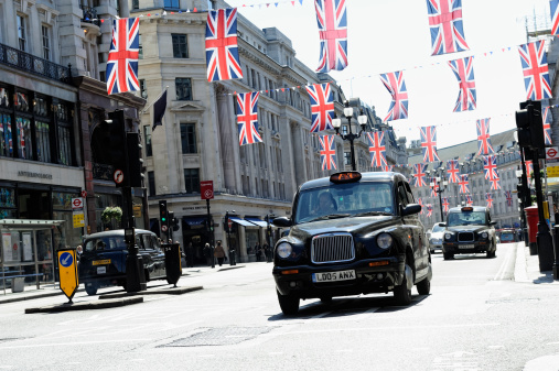 London, United Kingdom – October 21, 2022: A London street view full of traffic and people, with Westminster Abby and Big Ben in the background, on a sunny day in summer