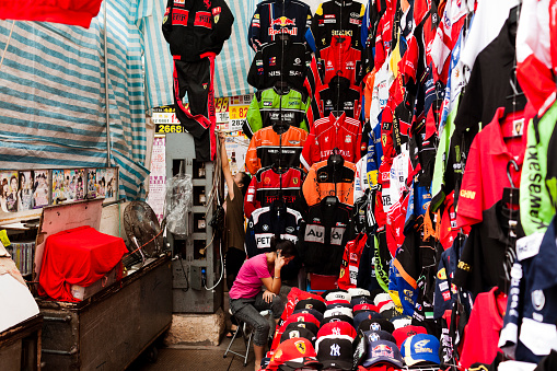 Hong Kong, China - September 28, 2011: Seller at her market stall in Mong Kok selling motorcycle clothing. this kind of street markets are very popular because the prices are usually much better than regular stores although many of the goods being sold are copies of the original brands.