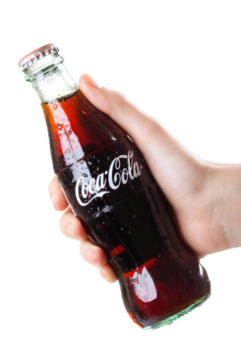 Izmir, Turkey - April 3, 2011: Hand holding classic 250ml glass Coca-Cola bottle. Coca-Cola is a carbonated soft drink sold in the stores, restaurants, and vending machines of more than 200 countries. It is produced by The Coca-Cola Company of Atlanta, Georgia