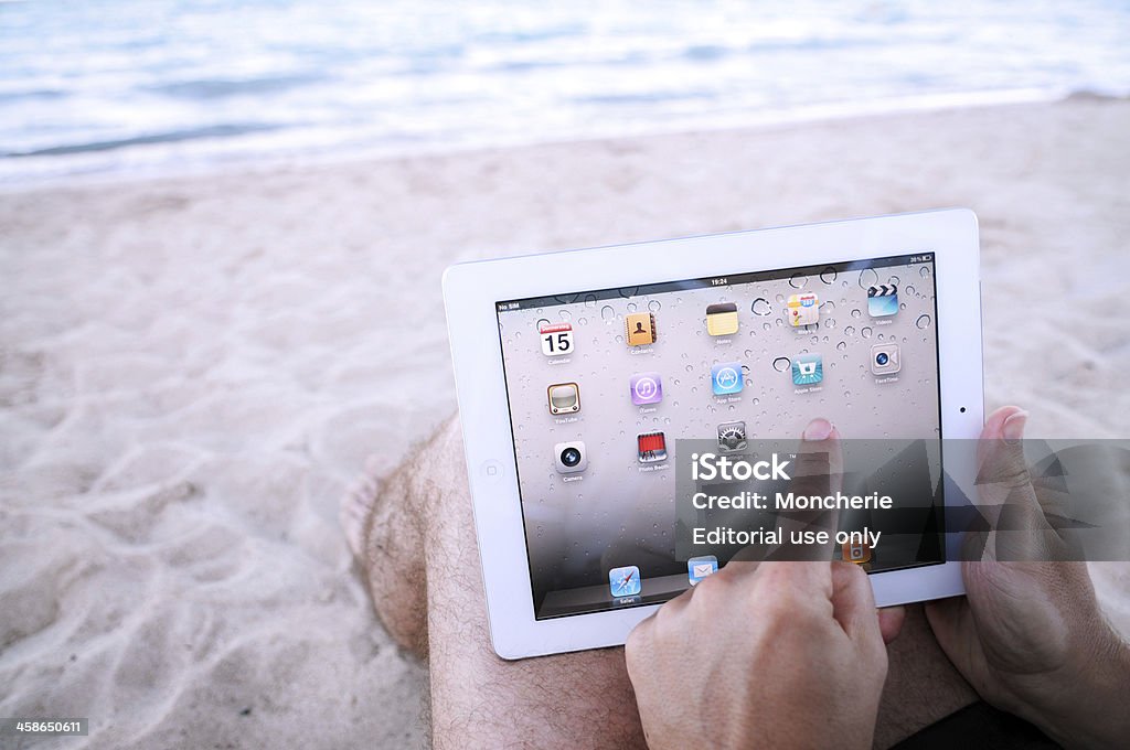 Człowiek dotykania iPadzie 2 głównym na plaży - Zbiór zdjęć royalty-free (Plaża)