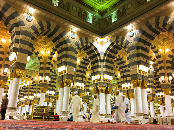 Interior of Masjid (mosque) Nabawi in Al Madinah. Al Madinah, Kingdom of Saudi Arabia-February 19, 2012: Muslim men walk on inside Masjid (mosque) Nabawi. Nabawi mosque is the 2nd holiest mosque in Islam. al masjid an nabawi photos stock pictures, royalty-free photos & images