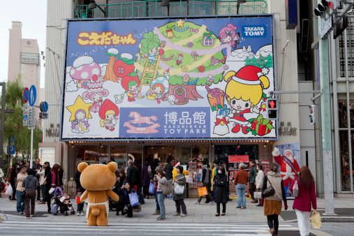 Tokyo, Japan - November 26, 2011: Pedestrians walk past the road outside the Hakuhinkan Toy Park. This toy park is located in 8-8-11 Ginza, Chuo-ku, Tokyo, Japan. It is the largest toy stores in Japan. A Japanese cartoon character Rilakkuma is outside the shop, many people taking photo for it.