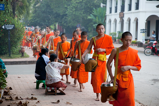 Senior monks stand and look to young monks during they walk on stair of the temple up to chapel or church to do some activity in early morning.