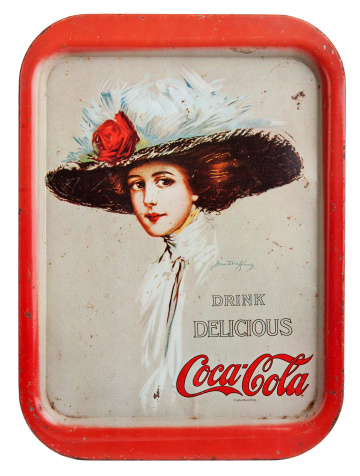 Carol Stream, IL, USA- November 5, 2011: A vintage Coca-Cola drink tray believed to be a reproduction from 1971 depicting a young women in a large hat. The original art was painted by Hamilton King.