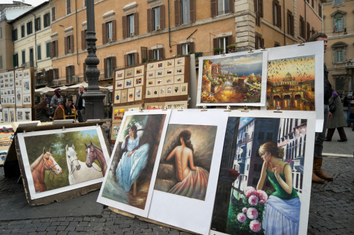 Rome, Italy - March 14, 2011: Street artists selling their art in Piazza Navona; the pictures in foreground are portraits of young women; over them Rome representations; on the left three horses
