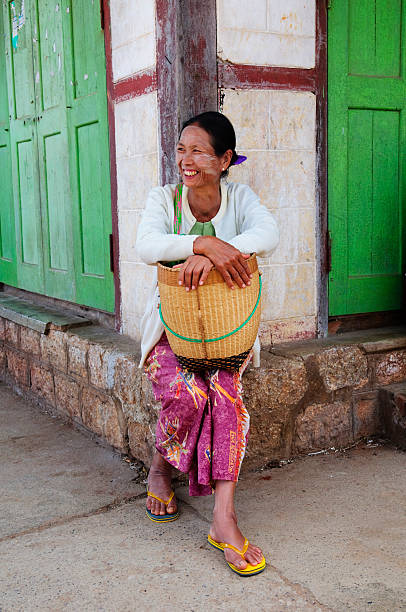 Kalwa, Myanmar - November 1, 2011: A Burmese woman smiles broadly as she waits on a street corner for a ride back to her village after leaving the Sunday market.