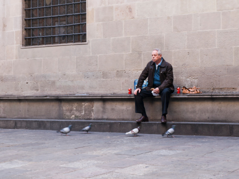 Barcelona, Spain - january 09, 2012: man is sitting and eating on the bench in historical centre in barcelona in january 2012