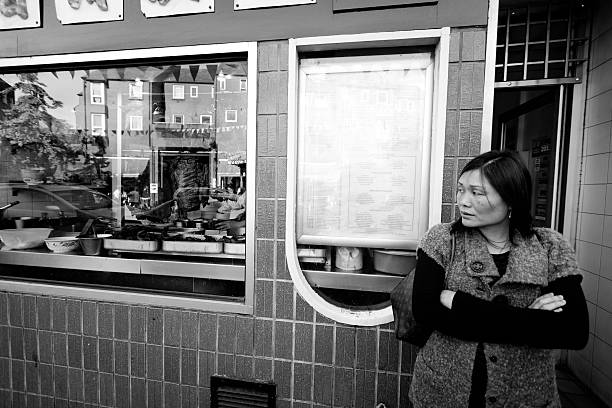 London, United Kingdom - May 2, 2011: Chinese woman outside a Chinese restaurant in China Town, London, United Kingdom.