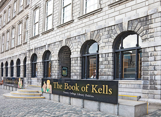 Trinity College Library, Dublin: home to the Book of Kells Dublin, Republic of Ireland - 14th July, 2011: The main public entrance to Trinity College in Dublin, with a poster outside indicating that this is the home of the Book of Kells, a famous illuminated Celtic manuscript of the Christian Gospels, dating from c800 AD. The Book of Kells was presented to Trinity College in 1661. trinity college library stock pictures, royalty-free photos & images