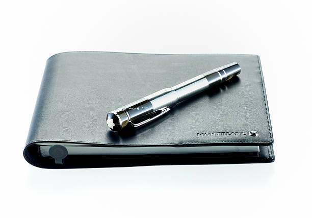 Leiden, The Netherlands - October 11, 2007: Product shot of a Montblanc William Faulkner fountain pen limited edition lying on a black leather Montblanc Squarish diary on white background. The Montblanc company was founded in Germany in 1908 and started with the production of luxury fountain pens. Today the company is an up market manufacterer of watches, jewellery, perfume, eywear and leather goods.