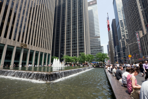 New York, USA - June 10, 2011: New Yorkers and tourist  in spring/summer time sitting at the fountain of one of the corporate skyscrapers at Sixht Avenue