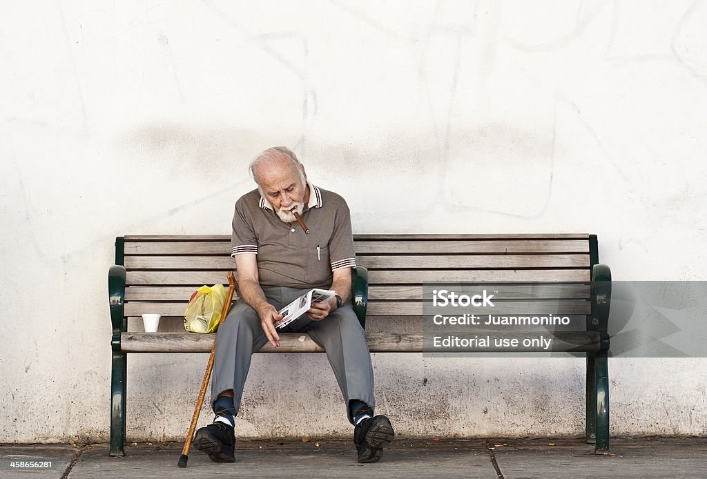 Eight Street Miami, Florida, USA - October 21, 2011: Senior hispanic man sitting in a public bench reading a newspaper and smoking a cigar in famous calle ocho,little havana,miami,florida 70-79 Years Stock Photo