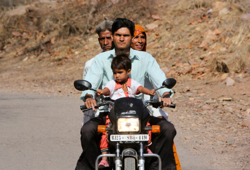 Ranthambhore National Park, India - April 18, 2012: Pilgrims on their way to the Ranthambhore Fort, where a special holiday was being commemmorated at the Temple of Ganesha. These pilgrims - probably family members - are on a motorcycle, and are just outside the entrance to Ranthambhore Fort.
