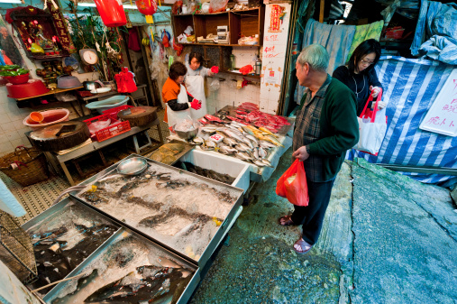 trays with scaled fish in the process of drying in the sun and in the air, typical of the town of Nazaré. Fish seller in activity sitting waiting for customers