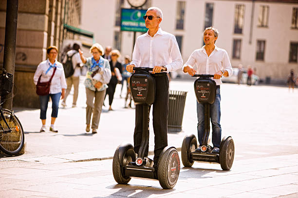 dois homens passeio de segway a piazza del duomo, milão, itália - segway - fotografias e filmes do acervo