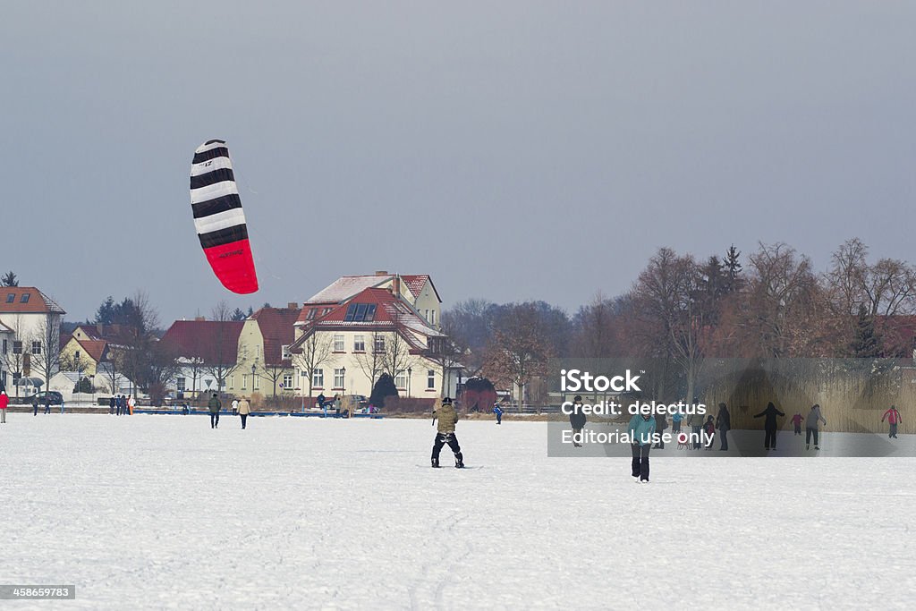 Ice skating on the lake Muellrose, Germany - February 12, 2012: Ice skating on the lake. People walking and skating on the frozen Great Lake Muellroser, Muellrose, Brandenburg, Germany. A man on a snowboard with a kite - Snowkiten. Ice-skating Stock Photo