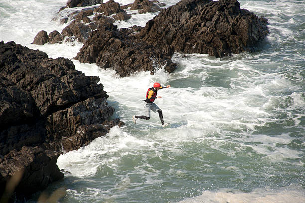 Coasteering "Croyde, North Devon, England - June 15th 2009: A man jumping into the ocean. This is part of an extreme sport called Coasteering. Coasteering is a coastal route sport where you will climb, scramble, traverse, swim, go through caves & crevasses, get washed around in the swell, jump and freefall your way to an adrenaline pumping time!" croyde photos stock pictures, royalty-free photos & images