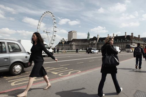 London, U.K.- May 3, 2011: pedestrians walking on Westminster Bridge. London Eye is at the background.