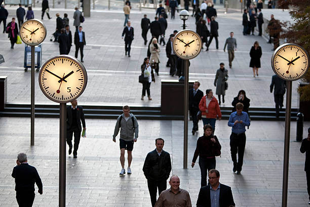 pedoni camminare in passato clock di canary wharf, il quartiere finanziario di londra - urgent parola inglese foto e immagini stock