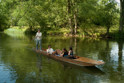 Oxford, United Kingdom - July 10th, 2011: Tourist punting on river Cherwell. Punting along Oxford lush canals and rivers is one of the most popular pastimes amongst both locals and tourists alike in summer.