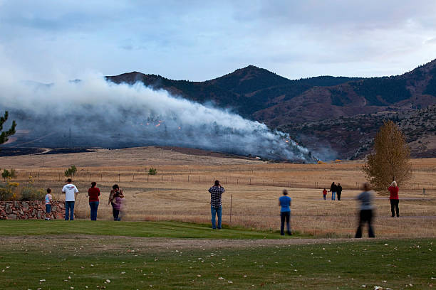 Littleton, Colorado, USA - October 9, 2010: Local residents  and families line up to watch a smoky forest fire burn in the Rocky Mountain foothills as pine trees and scrub oak go up in flames.
