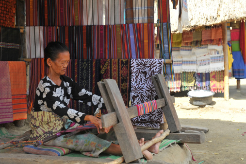 Laotian woman, wearing traditional Lantan tribe clothes, checking freshly dyed hand-woven cotton fabric in a Lantan village in Northern Laos