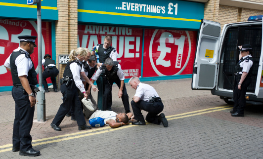Woolwich, London UK:August 8th 2011.5 male and three female Metropolitan Police officers arrest an uncooperative male prisoner outside a Poundland store in east London.