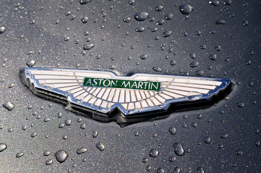 Nunspeet, The Netherlands - August 7, 2011: An Aston Martin badge is covered in raindrops. The badge is mounted to a gray Aston Martin DB7.