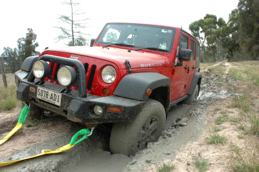 Border Track, Australia - March 13, 2011: Red 2007 Rubicon Jeep JK Wrangler stuck in mud on the border track between South Australia and Victoria. This Jeep is being recovered by using a snatch / tow strap