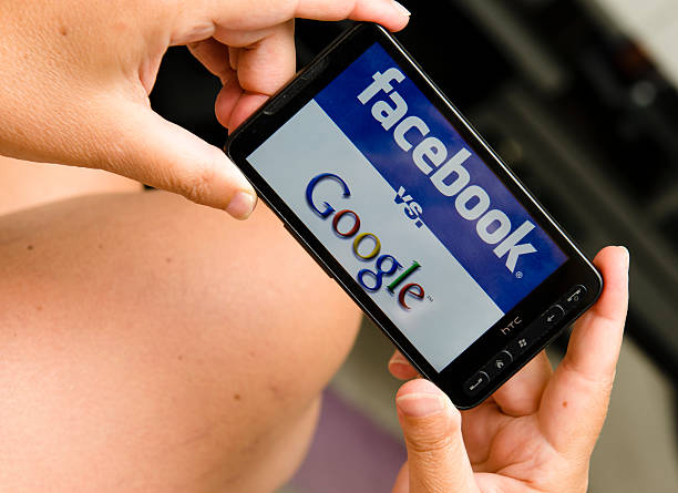 mujer sosteniendo un smartphone google y logotipo de facebook - google plus fotografías e imágenes de stock