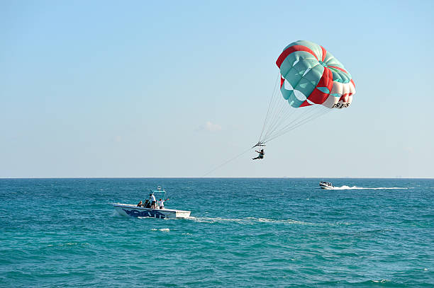 Playa del Maya, Mexico - February 3, 2011: A tow boat is lifting a woman into the air to go parasailing above the Mexican Caribbean coast of Playa del Maya.  This popular tourist destination in Mexico offers parasailing as one of many water sports available to visitors.