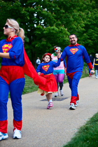 London, England - May 15, 2011: group of people including adults and a child, walking and running on a path through Regents Park as part of a charity fun run. Seen wearing fancy dress as there was a super hero theme for this 5 km run. The spirit of the event is to have fun and participants can walk or run. Large number of different charities supported.