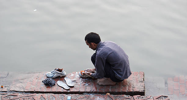 asiatischen mann waschen seine sneaker am ganges - shoe men indian culture indian ethnicity stock-fotos und bilder
