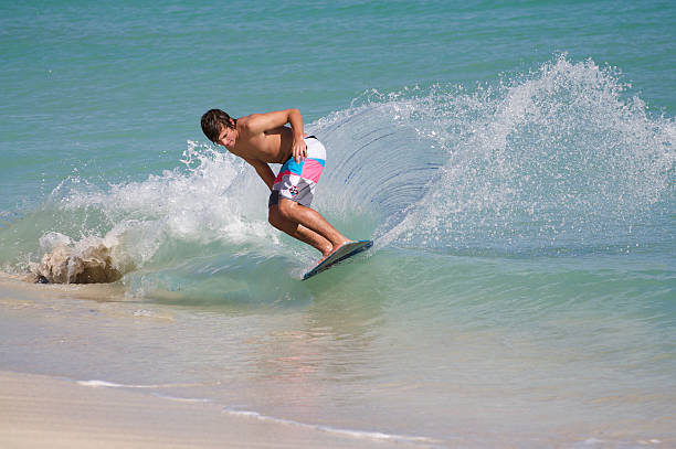 молодые skimboarder glides на майами-бич - skimboard стоковые фото и изображения