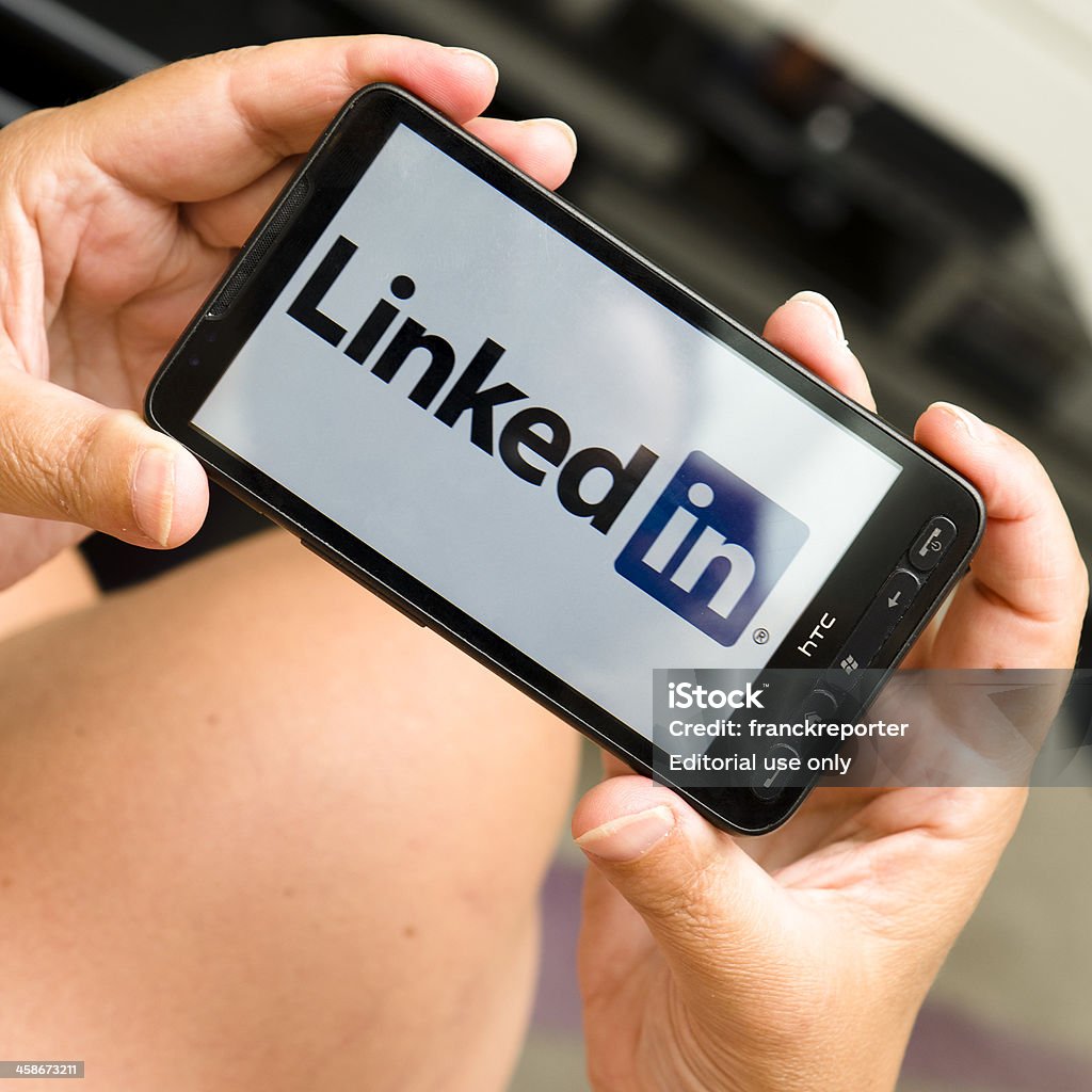 Женщина держит смартфон с Логотип linkedin - Стоковые фото LinkedIn роялти-фри