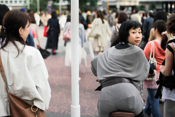 Tokyo, Japan, May 16th, 2010... Pedestrian people are crossing the Avenue near Shibuya... A young Japanese woman on her bicycle suddenly looking back and looking in to the camera... There thousands of people biking in Tokyo every day... Bicycles are a common vehicle for very young and very old people too...