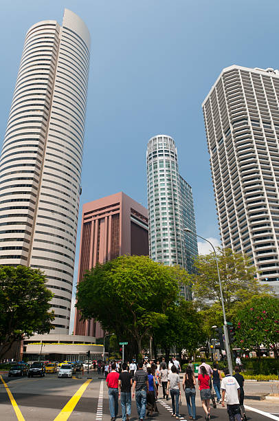 Singapore, Singapore - July 08, 2011: People crossing road at Center Business District with skyscraper as background.