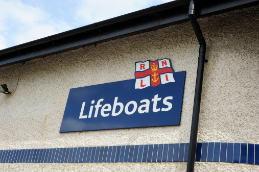 Swansea, UK - May 14, 2011: Since 1824, the Royal National Lifeboat Institution has coordinated all the search and rescue (SAR) units and decides whether to launch a lifeboat, scramble a helicopter or call out a mud or cliff rescue team or other group. It is manned by a mixture of paidt and voluntaryr staff and, as a registered charity, relies on donations to fund it. This sign is on the famous lifeboat house at Swansea, Wales, UK