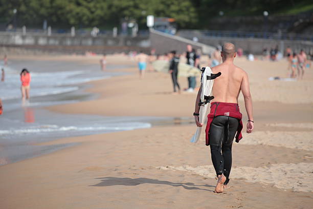 Surfer walking on the beach stock photo