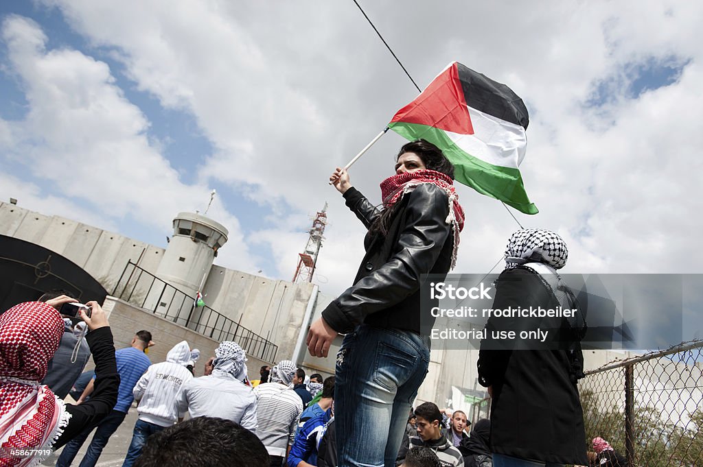Palestinian demonstration "Bethlehem, Occupied Palestinian Territories - March 30, 2012: A Palestinian young woman waves a flag near the Bethlehem checkpoint during Land Day protests in Bethlehem." Adult Stock Photo